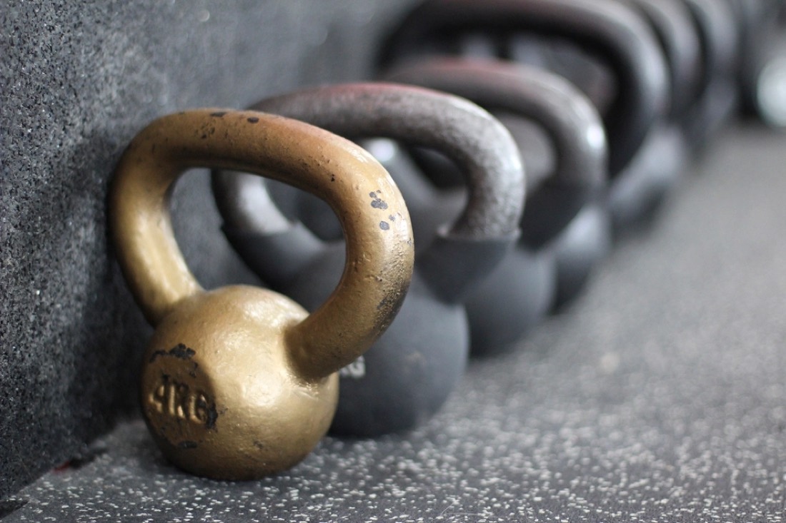 A row of kettlebells lined up on a gym floor